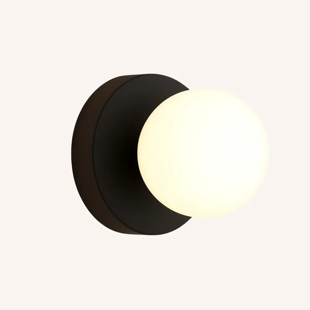 Applique murale scandinave avec base noire et globe en verre opale, lumière LED douce.
