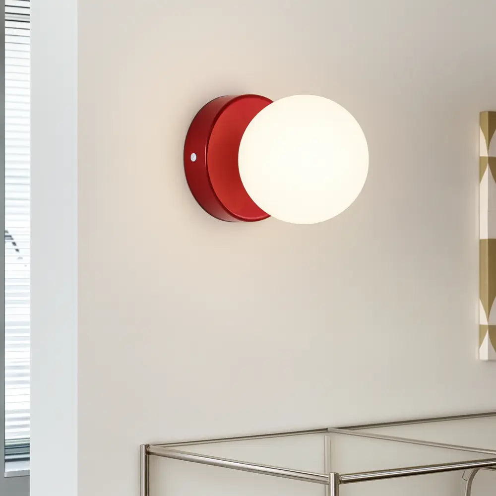 Applique murale ronde LED, base rouge, globe blanc opale, style scandinave élégant.