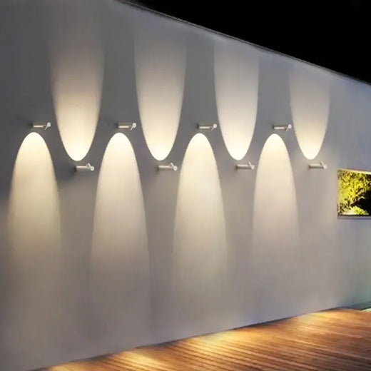 Luminaire mural LED blanc projette une lumière chaude symétrique haut et bas, effet ondulé.