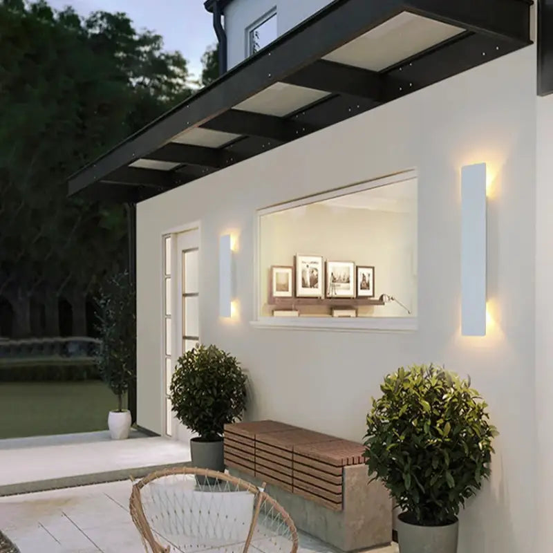 Deux appliques murales épurées en aluminium noir fixées sur un mur extérieur blanc.