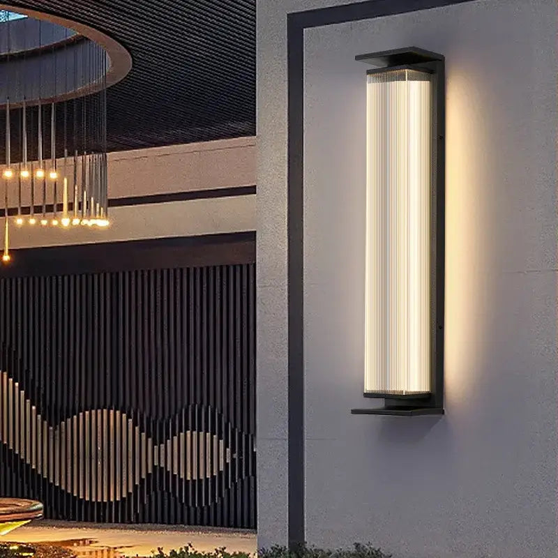 Applique murale extérieure noire avec grand abat-jour côtelé en verre et lumière LED chaude.