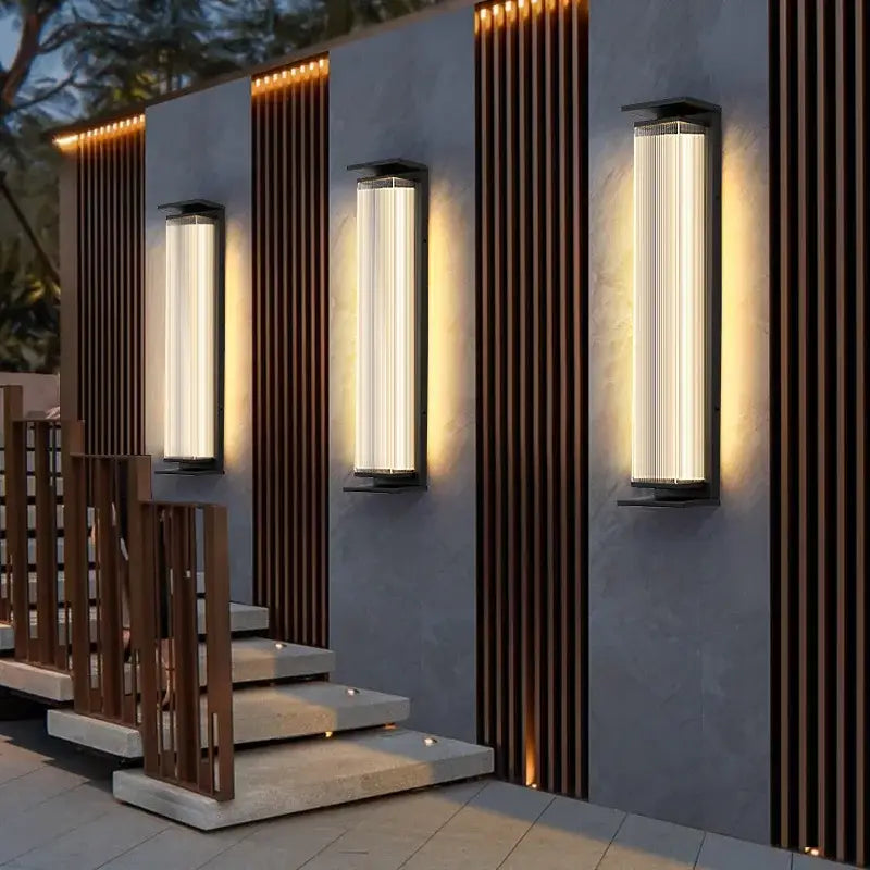 Luminaire mural extérieur noir moderne diffusant une lumière chaude et élégante en soirée.
