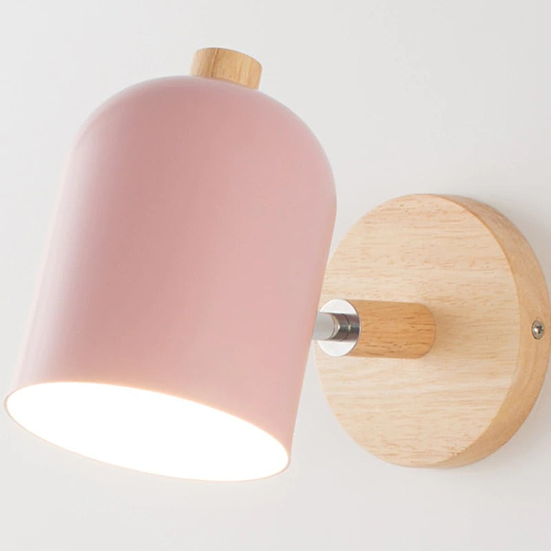 Applique murale nordique, base ronde bois clair, abat-jour dôme rose, lumière douce.