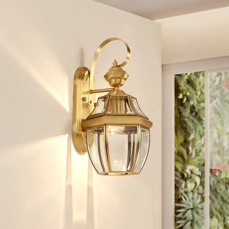 Lanterne murale dorée rétro hexagonale en verre et cuivre, émettant une lumière chaleureuse.