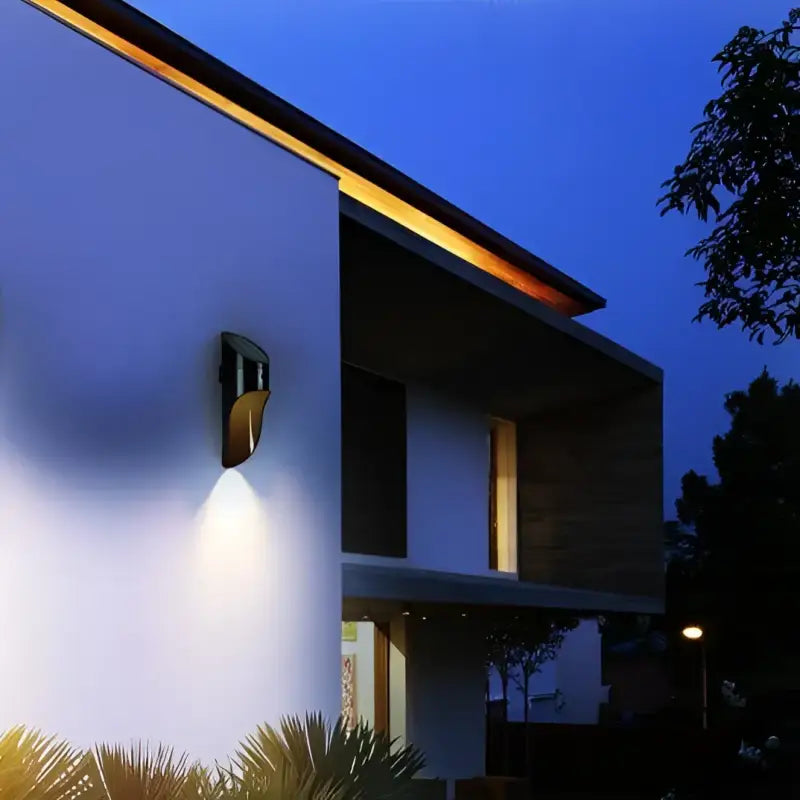 La LUMINAIRE MAISON Applique murale extérieur Solaire Blanc éclaire une façade moderne la nuit.