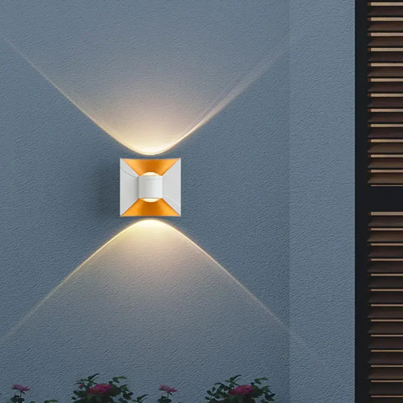 Applique murale extérieur noir incurvé diffusant une lumière LED chaude en forme de X.