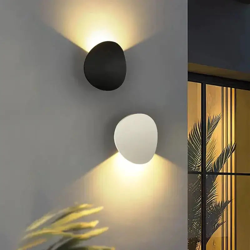 Deux appliques LED rondes en aluminium, une noire et une blanche, lumière chaude opposée.