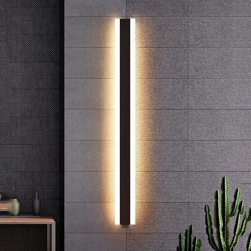 Le LUMINAIRE MAISON applique murale extérieur LED noire diffuse une lumière dorée chaleureuse.